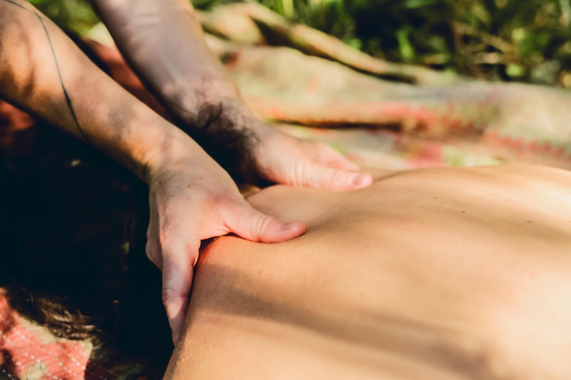 Back massage in the sun Close-up of hands easing tension along the back in soft sunlight